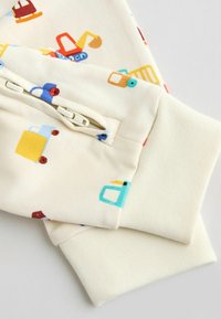 Svetlý rukáv mikiny s farebnými vzormi vozidiel. Tkanina je hladká s rebrovanou textúrou na rukávoch vrátane detailu so zipsom.