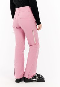 Roze skibroek van een gladde, rekbare stof. Voorzien van ritszakken en zijventilatie, met een aansluitend ontwerp en zwarte skibotten.