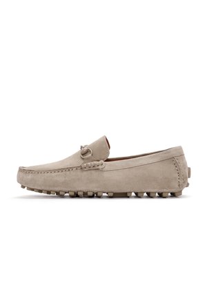 Mocasines de ante beige con un acabado suave, costuras decorativas y suelas de goma con tachuelas para mayor tracción. Presenta un sutil acento metálico.