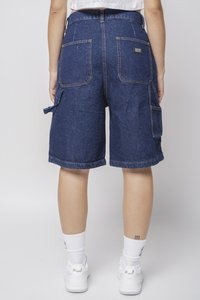 Mørkeblå denimshorts med en avslappet passform, som har to baklommer, broderte detaljer og oppbrettede ben. Satt sammen med hvite joggesko.