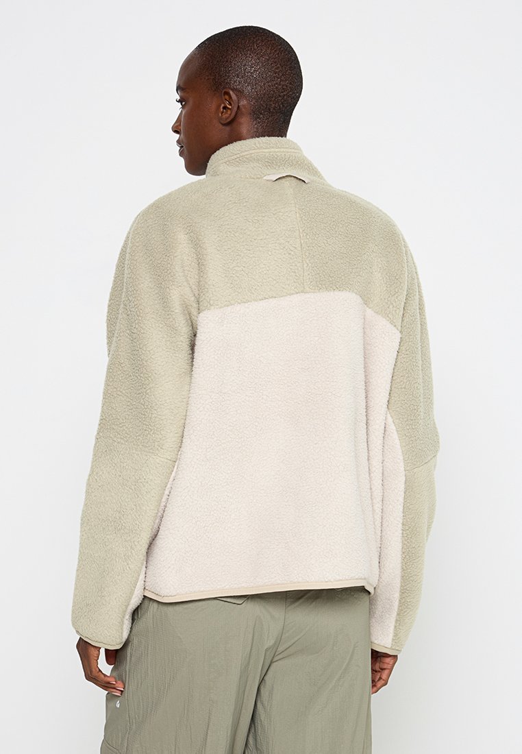 Hellbeige und olivgrüne Fleecejacke mit hohem Kragen, strukturiertem Stoff und einem Farbe-Block-Design, das eine lässige Passform bietet.