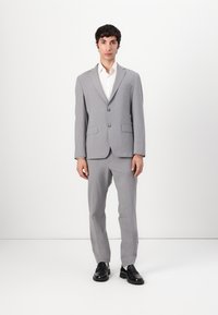 Grey two-piece suit made from textured fabric, featuring a single-button blazer and straight-leg trousers, paired with black shoes.