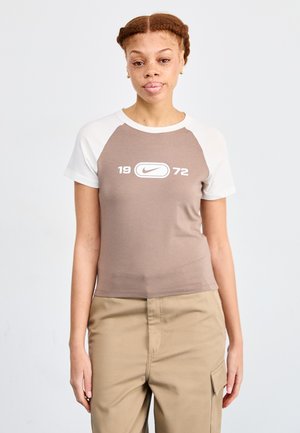 Brun och vit kortärmad t-shirt med rundad hals, med en central Nike-logotyp och siffrorna "1972" under.