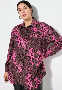 Hemd mit Knopfleiste im pinken und braunen Leopardenmuster. Lange Ärmel, eine Brusttasche, abgerundeter Saum und weicher Stoff.