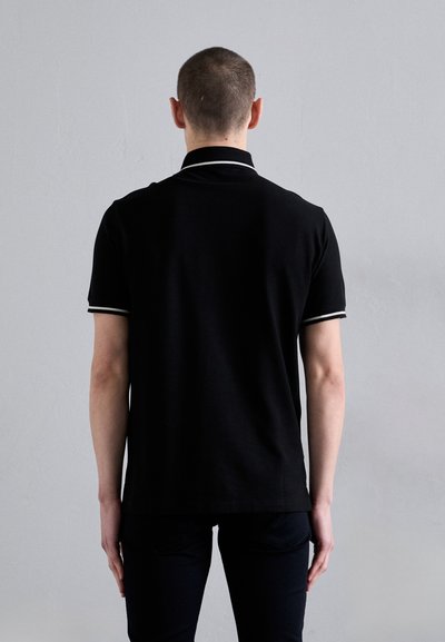 Black polo shirt with a slim fit, featuring a contrasting white stripe on the collar and sleeve edges. Smooth fabric, short sleeves.