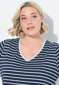 Top a righe navy con scollo a V e dettagli azzurri. Tessuto morbido, maniche corte, con strisce orizzontali bianche su uno sfondo navy solido.