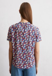 Kurzarmbluse in blau, rot und cremefarbenem Blumenmuster; leichter Stoff mit einem gefältelten Detail am Ausschnitt und einer lockeren Passform.