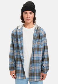Blauw en bruin geruite flanellen shirt met een grijze capuchon, ontspannen pasvorm, lange mouwen en knoopdetails, gedragen over een wit t-shirt.