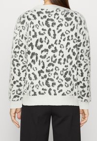 Weißer flauschiger Pullover mit schwarzem Leopardenmuster, gerippten Bündchen und Saum, im lässigen Schnitt und aus weichem Material. Rückansicht gezeigt.