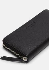 Schwarze Lederbrieftasche mit strukturierter Oberfläche, ausgestattet mit einem silbernen Reißverschluss und einem kleinen Reißverschluss-Zuggriff.