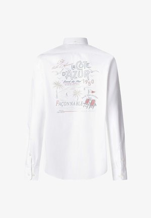 White long-sleeve shirt with colorful back print featuring palm trees, seagulls, sailboats, beach chairs, and French text about Côte d'Azur.