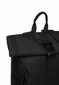 Black fabric backpack with a rolled top, adjustable straps, and a side zipper. Features a textured surface and a magnetic buckle closure.