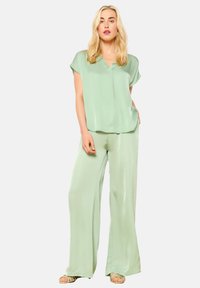 Light green, silky two-piece outfit featuring a loose-fitting top with cap sleeves and wide-leg pants. Smooth texture and relaxed fit.