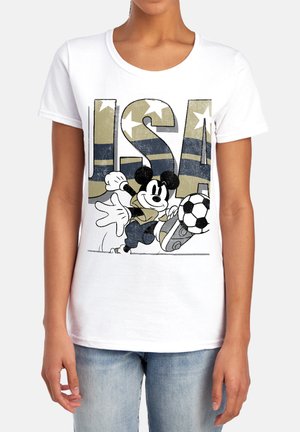 Person trägt weißes T-Shirt mit USA-Buchstaben und Mickey Mouse, der einen Fußball tritt, auf der Vorderseite bedruckt.
