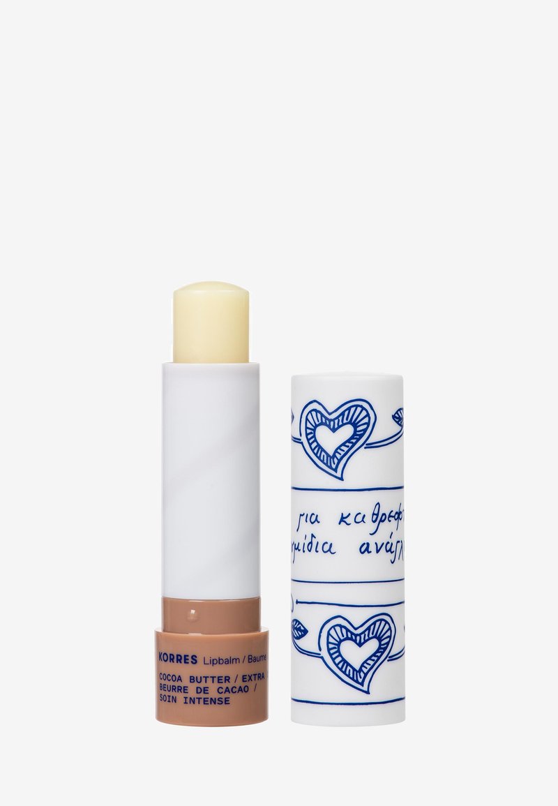 Kakaobutter-Lippenbalsam in einer weißen Tube mit blauen Herzmustern, mit einem beigen Grund. Der Balsam ist glatt und zylindrisch.