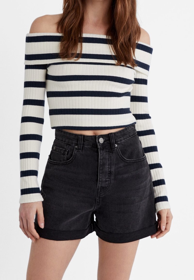 Pull cropped dégageant sur les épaules avec des rayures bleu marine et blanches ; associé à un short en denim noir taille haute avec des revers.