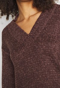 Strickpullover mit tiefem V-Ausschnitt, weichem Textil und einer satten Pflaumenfarbe mit strukturiertem Muster, designed in einer lässigen Passform.