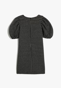 Svart klänning med vitt rutmönster, puffärmar och rund halsringning. Har en bakförslutning och textil med struktur.