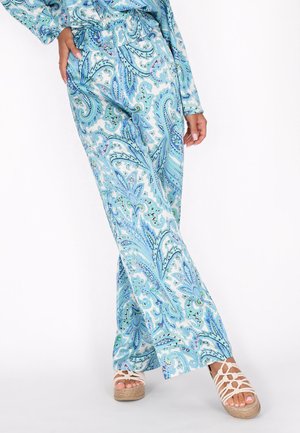 Pantaloni a gamba larga con motivo paisley blu e verde, dal tessuto morbido, con vita elasticizzata, abbinati a sandali con zeppa bianchi e cinturini.