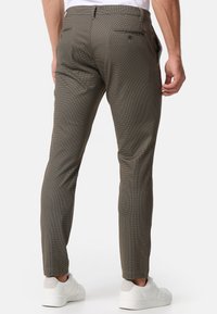Pantaloni da uomo su misura in tessuto a fantasia, design a quadretti marrone e beige, slim fit, con due tasche posteriori e dettagli di cucitura sottili.
