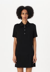 Vestito polo nero con maniche corte, patta con bottoni e orlo plissettato. Realizzato in tessuto morbido, presenta una vestibilità su misura.