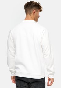 Witte sweatshirt van zachte stof, met lange mouwen, ribbelmanchetten en -zoom, en een eenvoudig, minimalistisch ontwerp zonder zichtbare logo's.