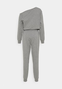 Grå jumpsuit med en cropped top med asymmetrisk udfoldning og lange ærmer, parret med tætsiddende ankel-lange bukser. Blød tekstur.