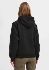 Felpa nera con cappuccio, dotata di polsini e orlo a costine, realizzata in un materiale morbido. Presenta un design senza cuciture sulla schiena e una finitura testurizzata.