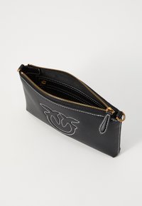 Sort læder clutch taske med hvid syning, guld lynlås og en diskret logo detalje foran. Rektangulær form, slank design.