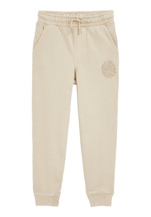 Beige joggingbukser i bomuld med elastik i taljen og snøre, sidelommer, opsmøgede ankler og rundt trykt logo på venstre lår.