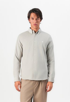 Light gray button-up shirt with a textured finish, featuring a folded collar and a small embroidered logo on the chest.