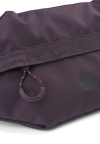 Lila Stofftasche mit strukturierter Oberfläche, einem Reißverschluss und einem Zugschlauf. Auf der Vorderseite befinden sich runde schwarze Akzente. Langlebiges Design.