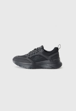 Black athletic shoes with a textured synthetic upper, prominent cushioned sole, and reflective laces. Features branding on the side.
