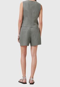 Haut sans manches en lin gris avec un design ajusté et une fermeture éclair dans le dos, associé à un short assorti. Comprend des poches minimalistes et des sandales simples.