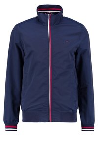 Mörkblå zip-up jacka med röda, vita och mörkblå randiga detaljer på kragen, ärmarna och dragkedjan, med en liten logotyp på bröstet.