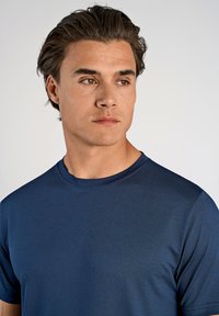 Marineblå crew-neck t-shirt med en struktureret overflade, der har korte ærmer og en subtil glans. Letvægts og åndbart materiale.
