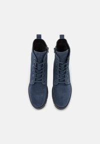 Stivaletti alla caviglia in suede blu navy con design lacciato, zip laterale, punta rotonda e suola in gomma testurizzata. Presenta occhielli metallici per i lacci.