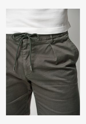 Donkergrijze shorts van lichtgewicht stof, met een verstelbare trekkoord met metalen accenten en zijzakken. Eenvoudig ontwerp.