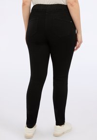 Jeans neri elasticizzati con una vita alta e elastica, due tasche posteriori e una forma della gamba slim. Tessuto morbido, adatto per un look casual.