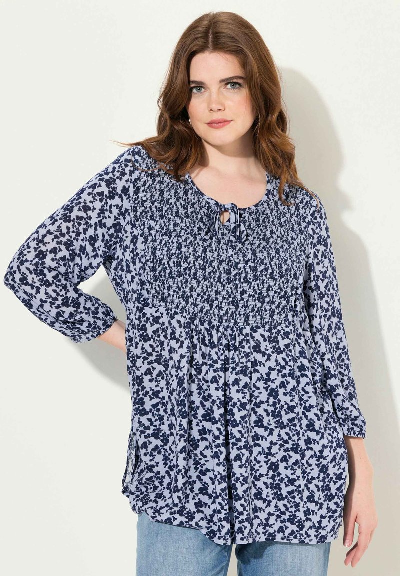 Blusa floreale blu con busto smock, scollatura con laccetto a chiave e maniche a tre quarti in un fit rilassato. Tessuto morbido e leggero.