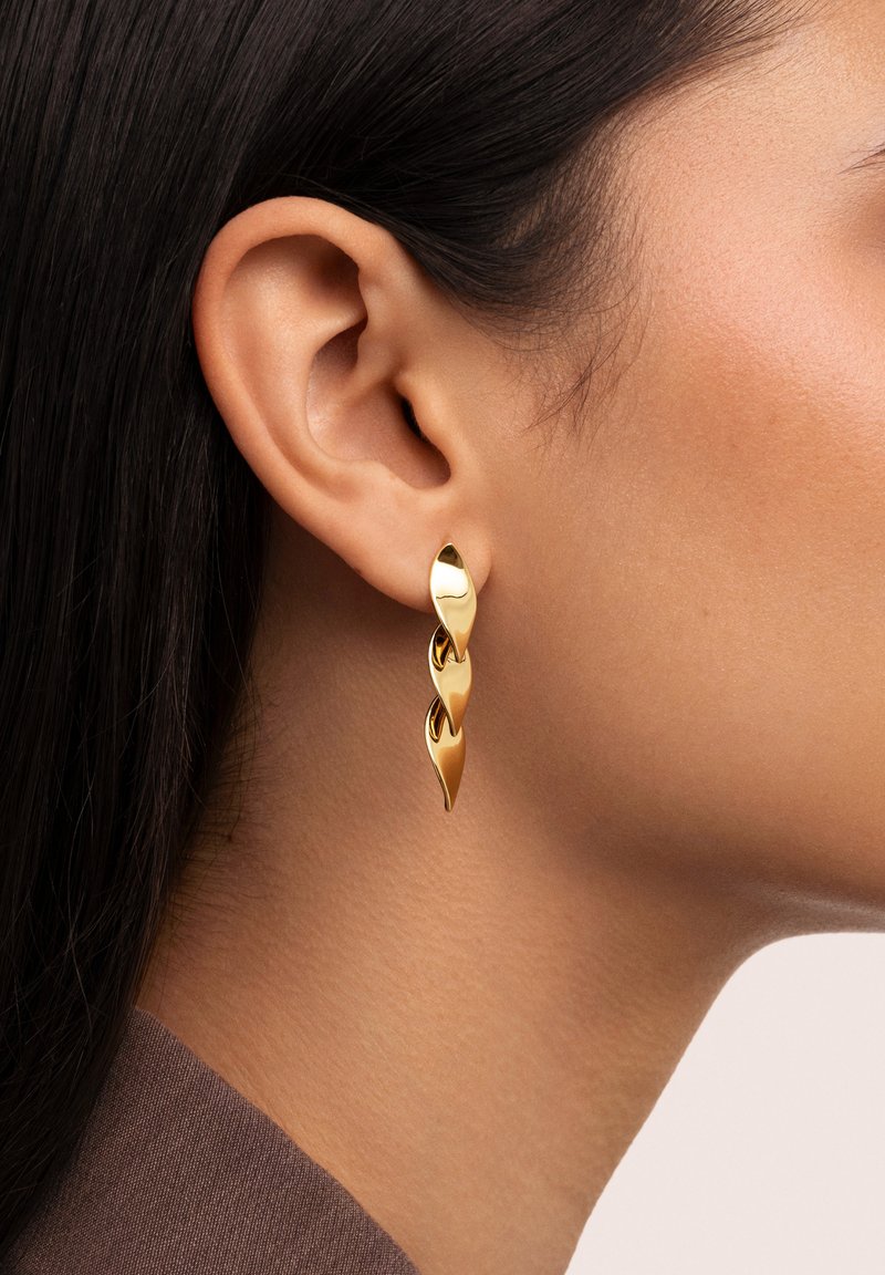 Pendientes de oro en forma de gota con un diseño retorcido, que cuentan con superficies lisas y reflectantes y una forma delgada y alargada.