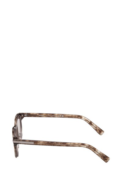 Occhiali da sole marrone tartarugato con forma rotonda e finitura lucida e liscia. Presentano aste sottili con accenti metallici.