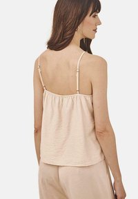 Top de tirantes ajustables en color rosa empolvado, con tejido texturizado y corte relajado. Presenta un diseño de espalda fruncida para mayor comodidad y transpirabilidad.