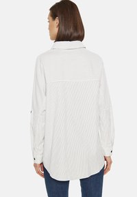 Camisa de manga larga en tejido ligero con rayas verticales en blanco y gris, con cuello de punta y mangas con puños.