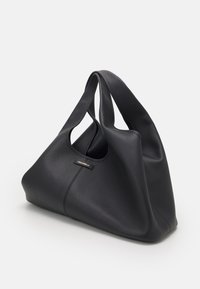 Czarna skórzana torba na ramię o gładkiej fakturze, z zakrzywionymi uchwytami i dyskretną tabliczką z logo. Charakteryzuje się przestronną, miękką strukturą.