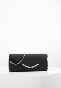 Mustan tekonahkainen clutch, jossa on hopeinen ketjuolkaimen, kaareva metallinen yksityiskohta ja kirjekuorimainen läppäkiirus. Sujuva pinta.