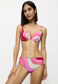 Zestaw bikini z różowo-kremowymi falistymi wzorami, miękką tkaniną, wyjmowanymi wkładkami, regulowanymi związaniami po bokach dolnej części oraz metalowymi akcentami.