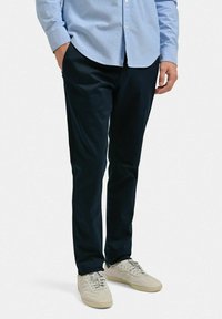 Marinblå chinos med en slät yta, smal passform, sidofickor och kombinerade med ljusa sneakers.