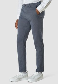 Grå texturerade byxor med tapered passform, med knappstängning och sidofickor, kombinerat med vita sneakers.