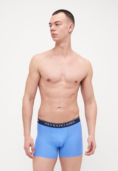 Siniset boxerit, jotka on valmistettu joustavasta kankaasta, jossa on laivastonsininen vyötärönauha, jossa lukee "POLO RALPH LAUREN". Sujuva texture ja istuva malli.
